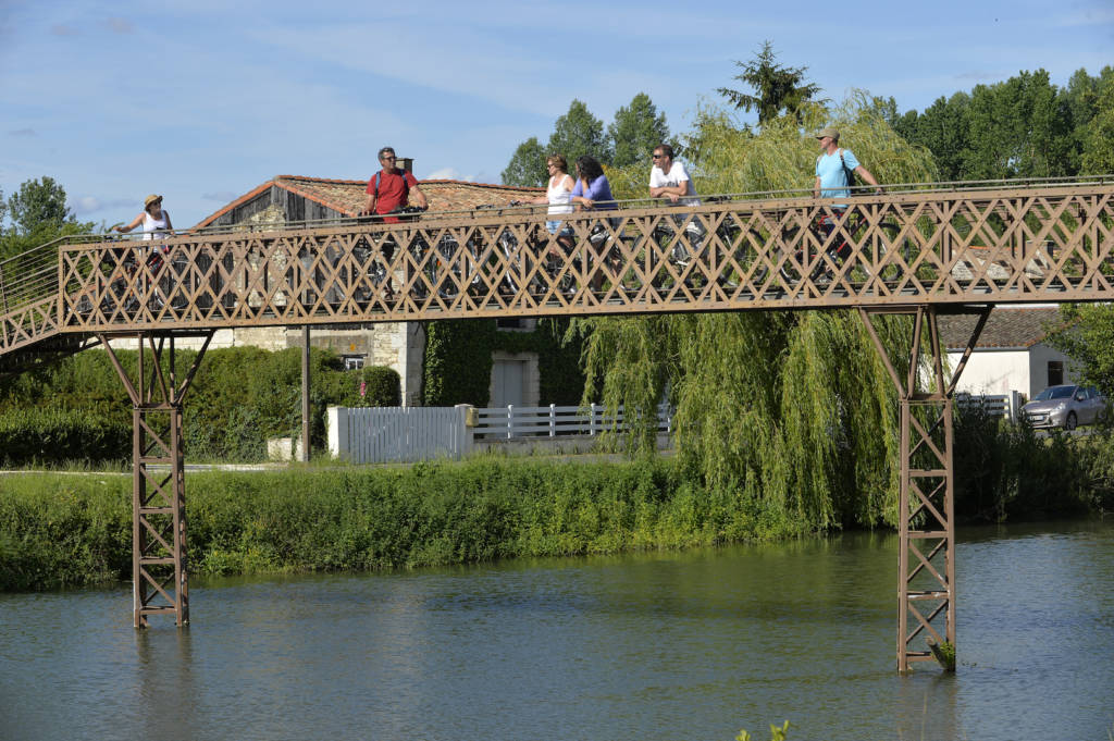 Touristes à vélo sur la passerelle de la Sèvre dans le Marais poitevin