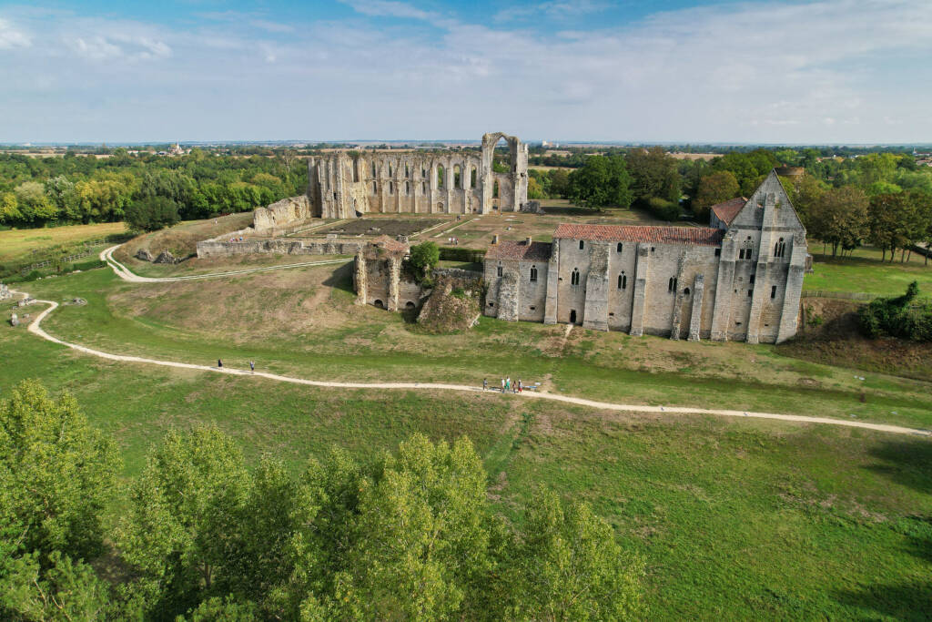Vue aérienne de l'abbaye de Maillezais avec des randonneurs sur le chemin